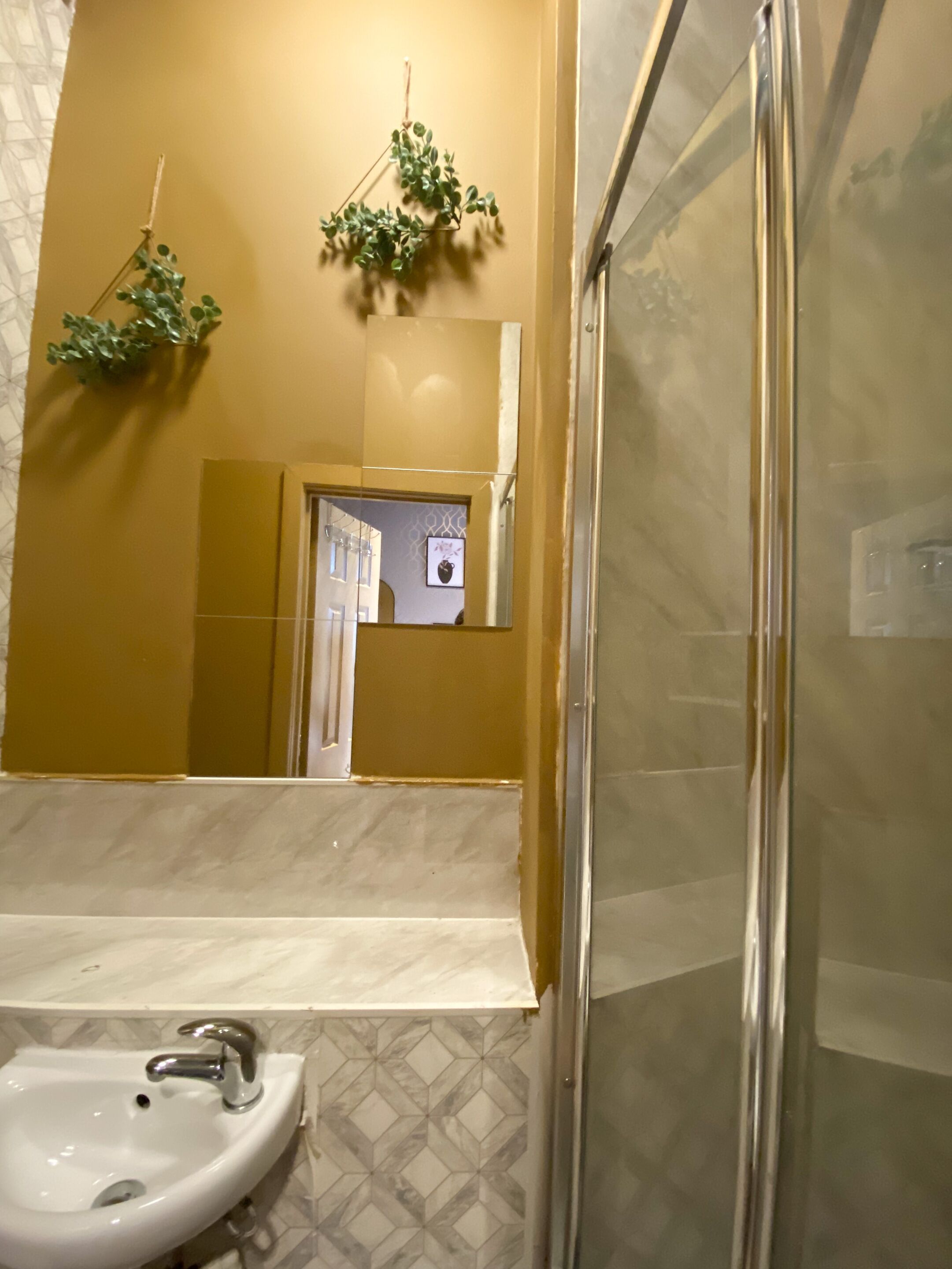 Een badkamer met een wastafel, spiegel en douche.