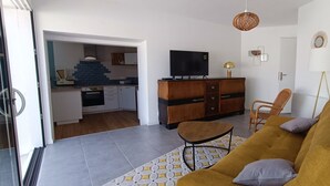 Una sala moderna con un sofá, una mesa de comedor y una cocina visible al fondo.