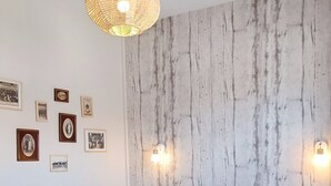 Un dormitorio con una cama de madera, pared con textura e iluminación en la pared.