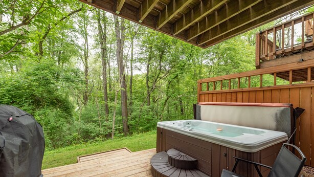 Un jacuzzi en una terraza de madera con vista a un bosque.