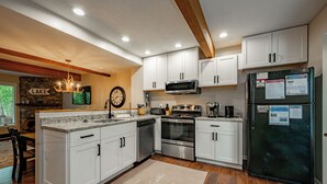 Una cocina moderna con armarios blancos, electrodomésticos de acero inoxidable y una pared decorativa de piedra.