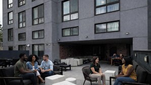 An outdoor seating area with modern furniture and a building with large windows in the background. - Dutch Hotel Long Island City New York , Belvilla District 6 Formerly Sonder (New York)