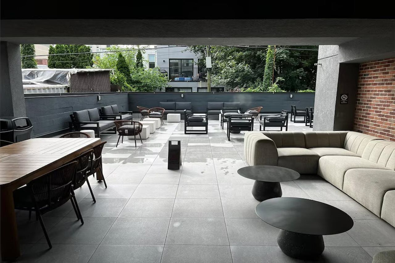 Un patio al aire libre con mesa de comedor, sillas, sofás y una mesa baja.