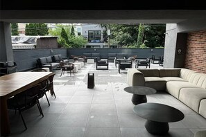 An outdoor patio area with a dining table, chairs, sofas, and a coffee table. - Dutch Hotel Long Island City New York , Belvilla District 6 Formerly Sonder (New York)