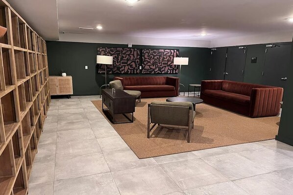 A modern lounge area with a sofa, armchairs, a coffee table, and a bookshelf. - Dutch Hotel Long Island City New York , Belvilla District 6 Formerly Sonder (New York)