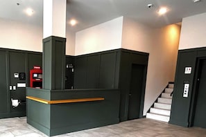 Un espace d’accueil avec un comptoir, une machine rouge et un escalier.
