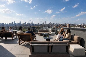 A rooftop terrace with seating arrangements, a city skyline view, and a clear sky. - Dutch Hotel Long Island City New York , Belvilla District 6 Formerly Sonder (New York)