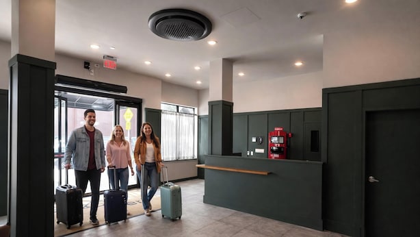 A lobby with a reception desk, a fire extinguisher, and a door with an emergency exit sign. - Dutch Hotel Long Island City New York , Belvilla District 6 Formerly Sonder (New York)
