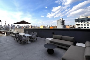 Une terrasse sur le toit, aménagée avec du mobilier d’extérieur, une table et un parasol.