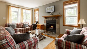 Una sala de estar acogedora con chimenea, sofás de cuadros y una mesita de centro.