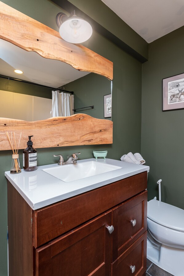 A bathroom with a wooden vanity, a white sink, a mirror, and a toilet. - Cozy, charming cottage 7 mins from Mount Snow and Lake Whitingham (Wilmington)
