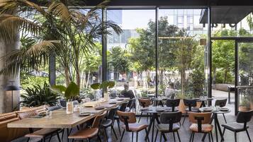 Un espace de restauration intérieur doté de grandes fenêtres, de tables en bois et de chaises noires.