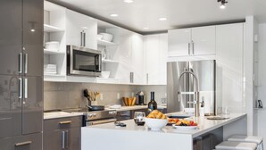 A modern kitchen with stainless steel appliances, white cabinetry, and a central island with seating. - Outpost: Timber Ridge 9 - Spacious Deck, Hot Tub & Pool Access! (Teton Village)