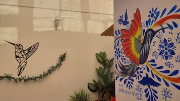 Un muro con un murale geometrico a forma di colibrì e un dipinto di un uccello dai colori vivaci.