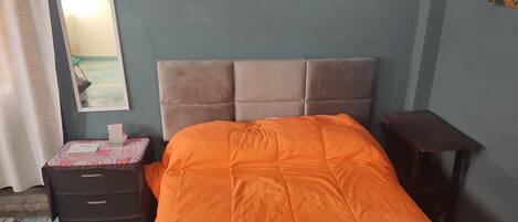 Un dormitorio con una cama, un aparador, un espejo y una mesita.