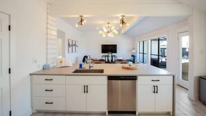 Een moderne keuken met een centraal eiland, inbouwapparatuur en grote ramen.