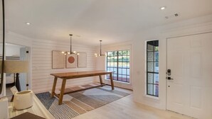 Een modern interieur met een houten bank, een witte deur en een uitzicht door een raam.