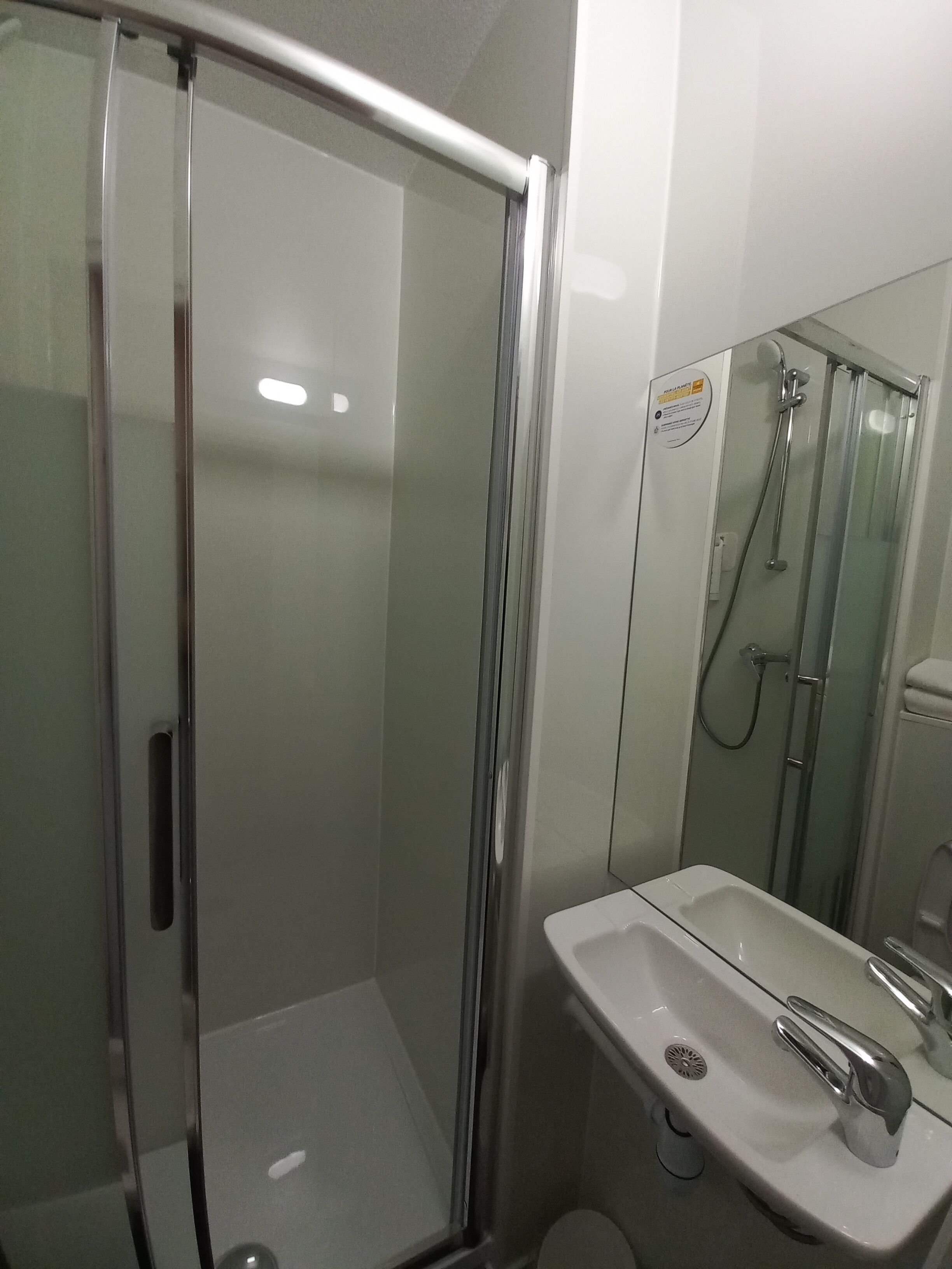 Een moderne badkamer met een douchecabine van glas, een wit wastafelmeubel met één kraan en een toilet.