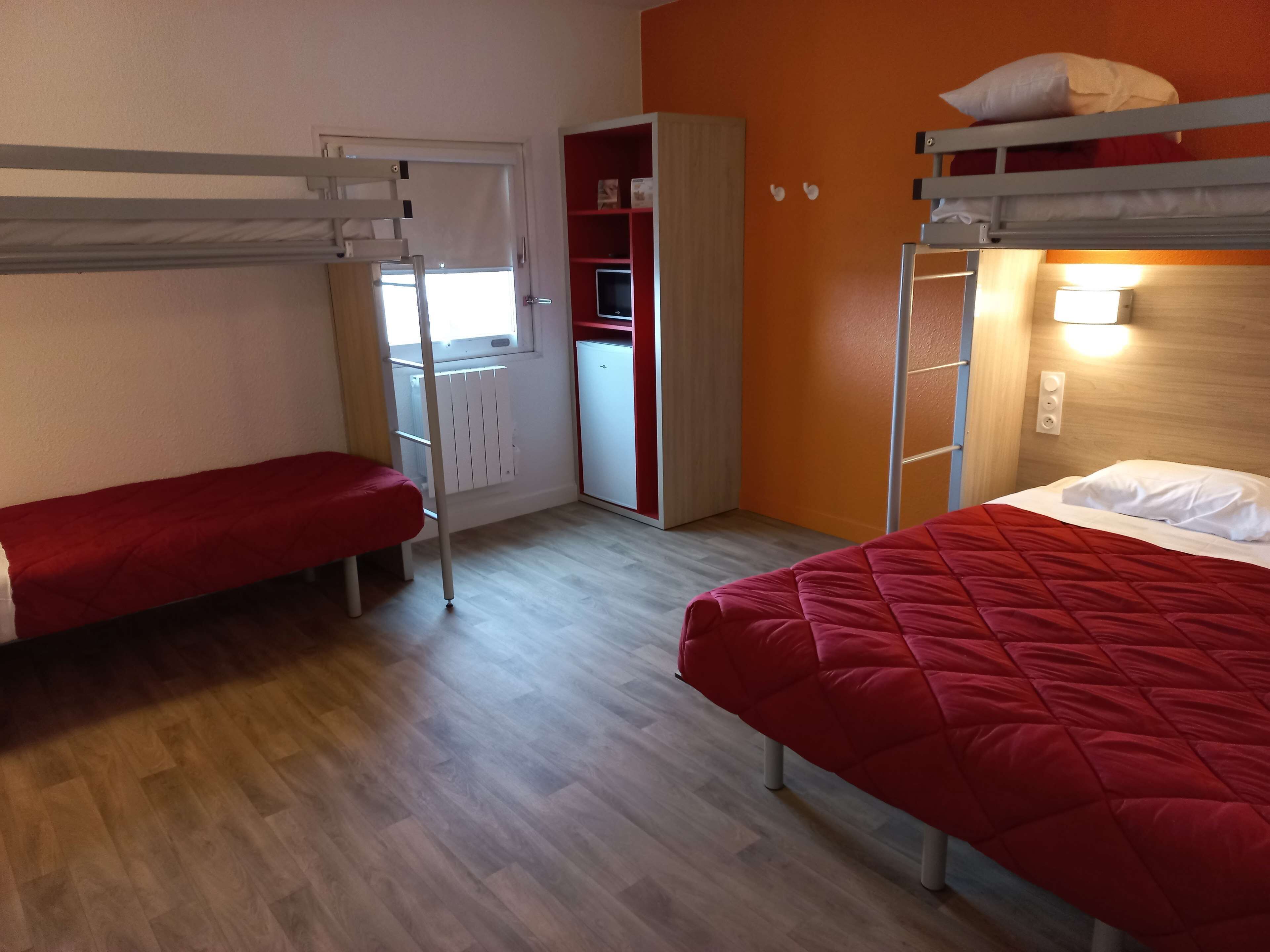Un dormitorio con dos literas, un armario y una pequeña kitchenette.