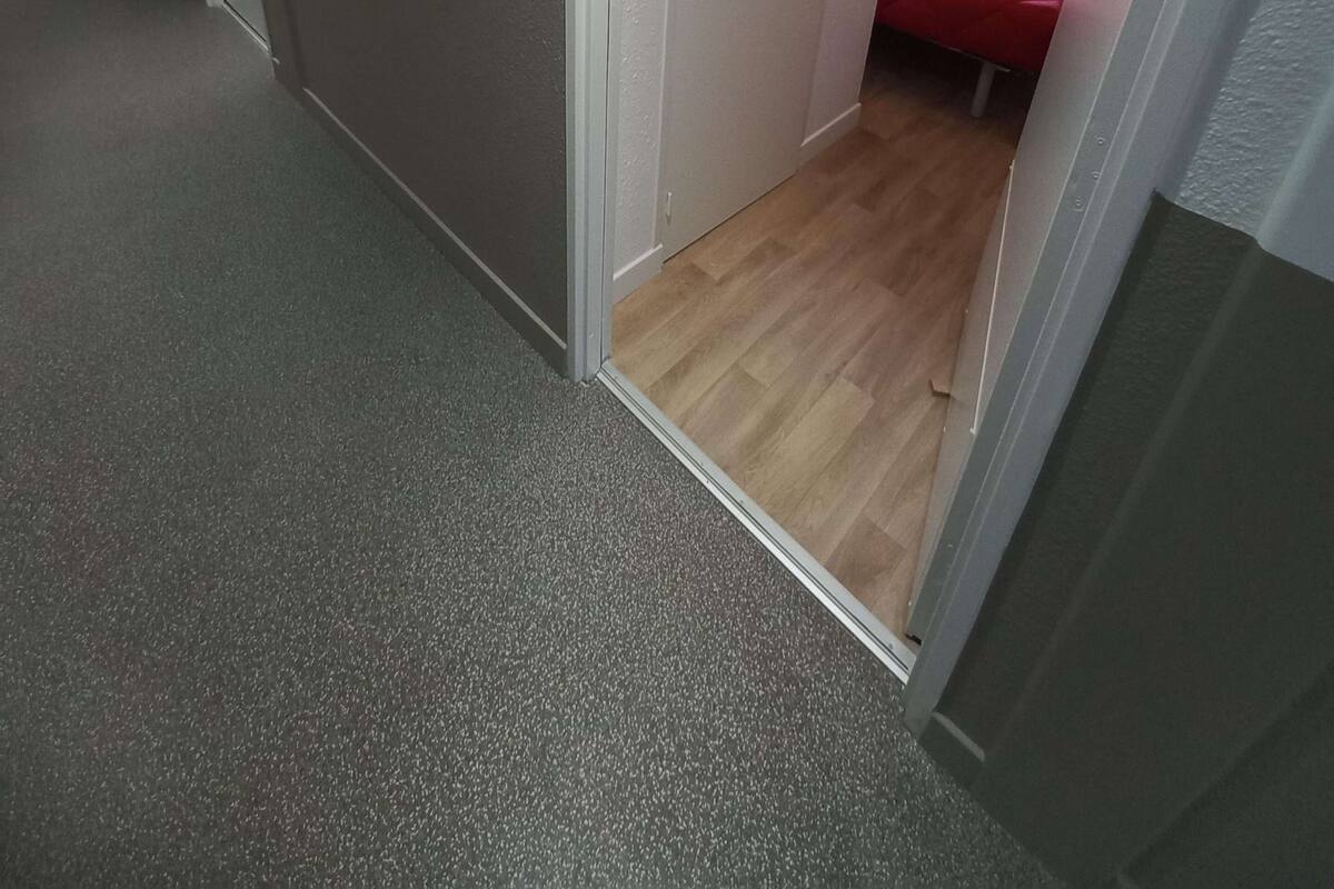 Ein Zimmer mit einem Bett, einem Fenster und einer Tür zu einem anderen Raum.
