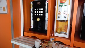 Een koffieapparaat en een drankautomaat in een kamer met oranje wanden.