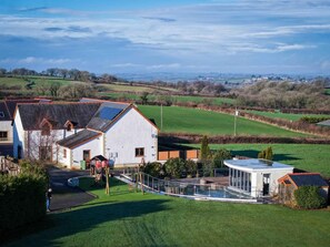 A modern house with a solar panel, a swimming pool, and a well-maintained lawn. - Knights Rest - 4 Bed Holiday Home - Princes Gate (Narberth)