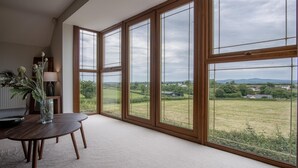 Ein Zimmer mit großen Fenstern und Blick auf eine ländliche Gegend.