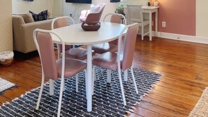 Comedor con una mesa redonda, sillas, una araña y un televisor.