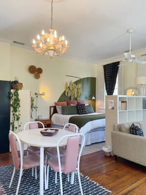 A cozy bedroom with a bed, bedside table, and a hanging light fixture. - 1885 Upscale Vintage Parlor Loft: Steps from Pulaski Square (Savannah)