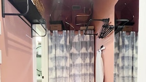 Un pasillo estrecho con suelo de madera, techo con lámparas colgantes y una puerta que da a un baño.