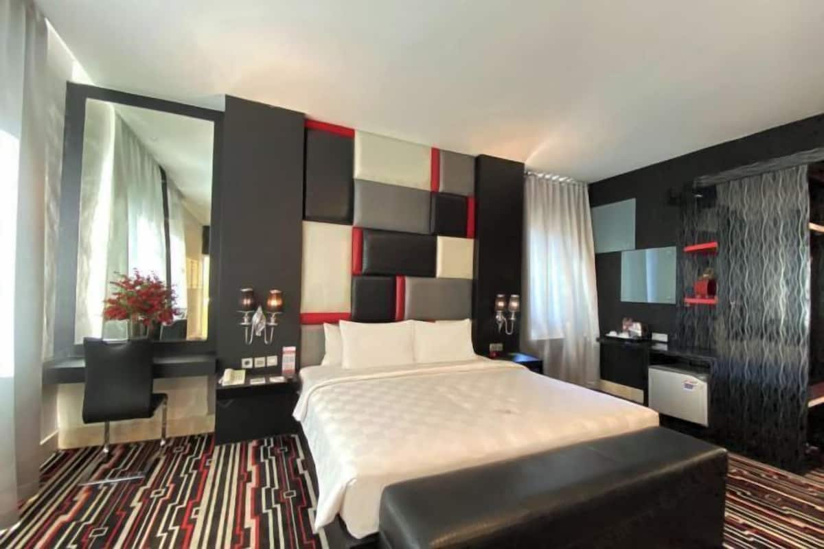 A modern hotel room with a large bed, a desk, and a mirror.