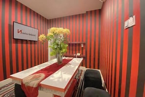 Een vergaderruimte met een lange tafel, stoelen, een vaas met gele bloemen en een bordje met Swiss-Belhotel.
