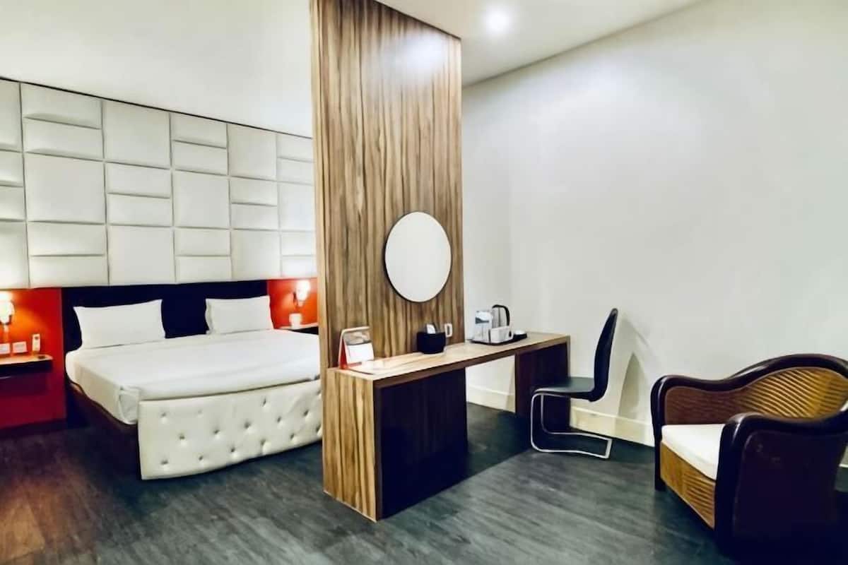 A modern hotel room with a bed, a desk, a chair, and a large mirror.