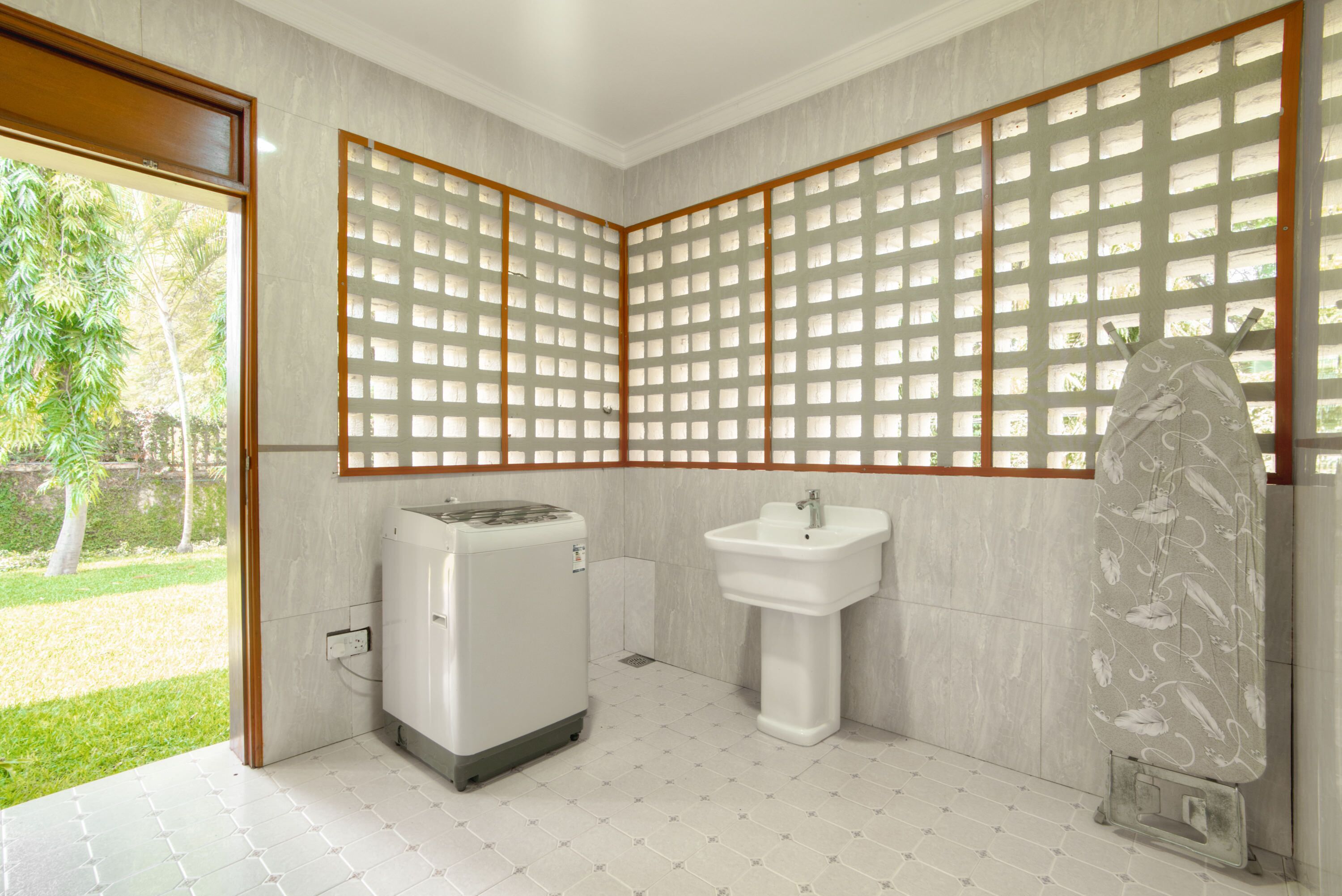 A bathroom with a large window, a washing machine, a sink, and a decorative stone.