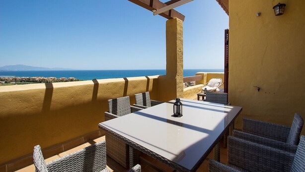 Una terraza con una mesa y sillas, con vista al mar.