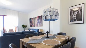 Una sala de estar moderna con una mesa de comedor de madera, sofá azul y obras de arte en las paredes.