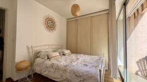 Una camera da letto con un letto, un elemento decorativo a parete, un cesto di vimini e una finestra con tende.