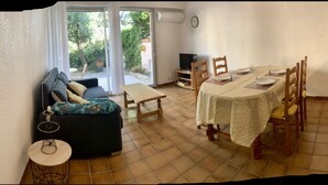 Un'accogliente zona giorno con un divano, un tavolo da pranzo per quattro persone e un angolo cottura.