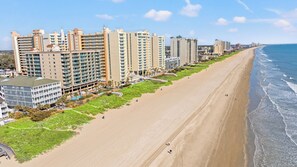 Un hotel costero con varios edificios altos, una playa de arena y una vista despejada del océano.