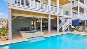 A two-story house with a swimming pool, outdoor seating, and a covered patio area.