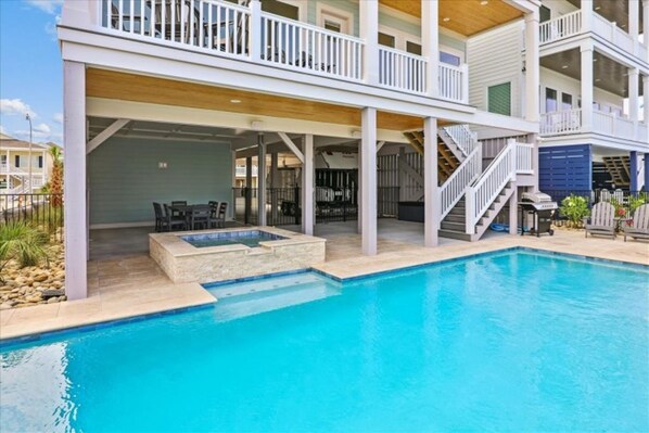 Une maison à deux étages dotée d’une piscine, d’un espace extérieur aménagé pour se détendre et d’un patio couvert.