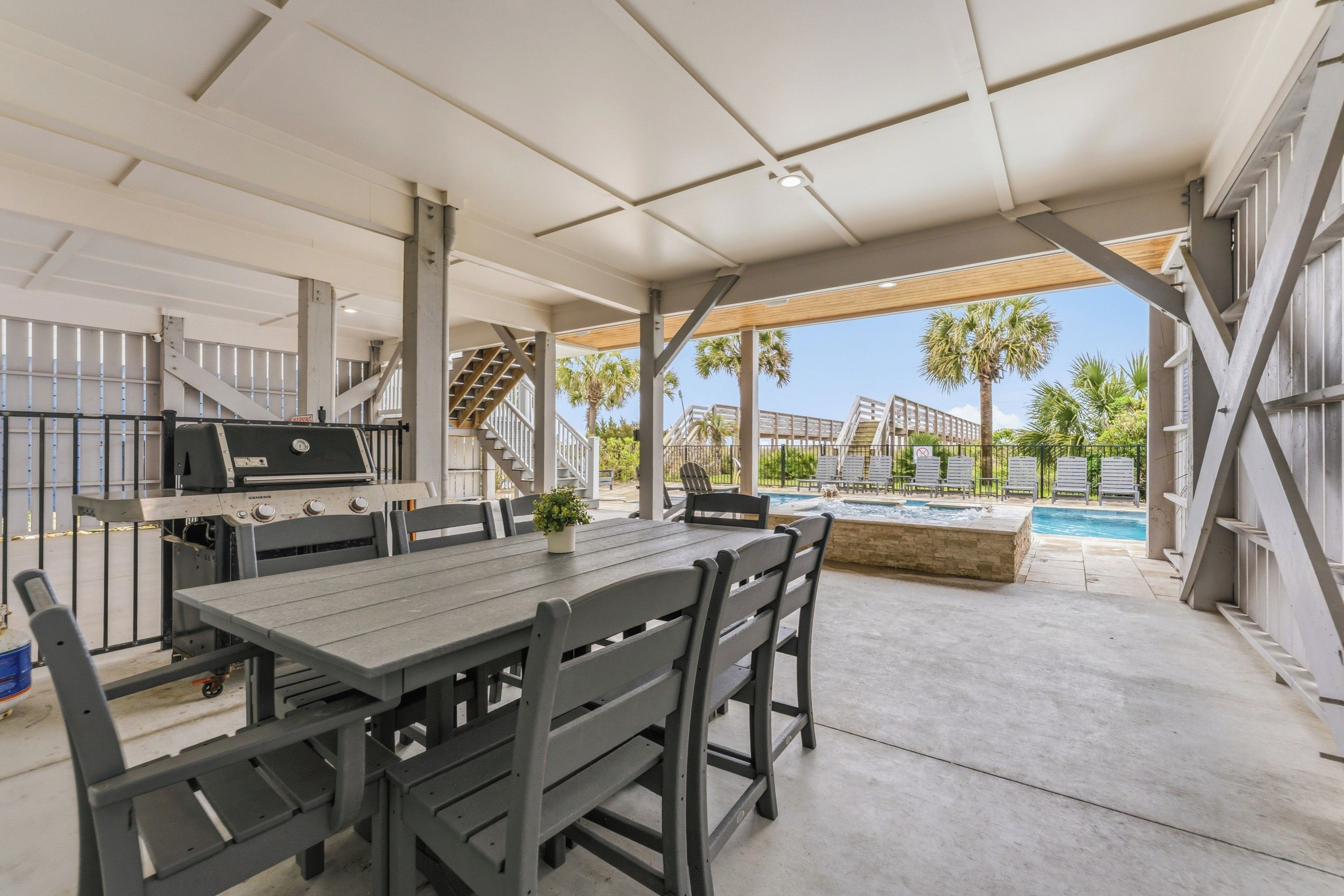 An outdoor patio with a dining table and chairs, a barbecue grill, and a pool area with lounge chairs.