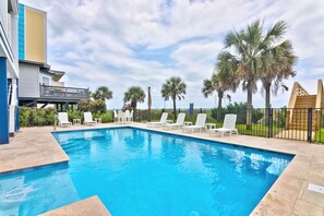A swimming pool with white lounge chairs and palm trees.