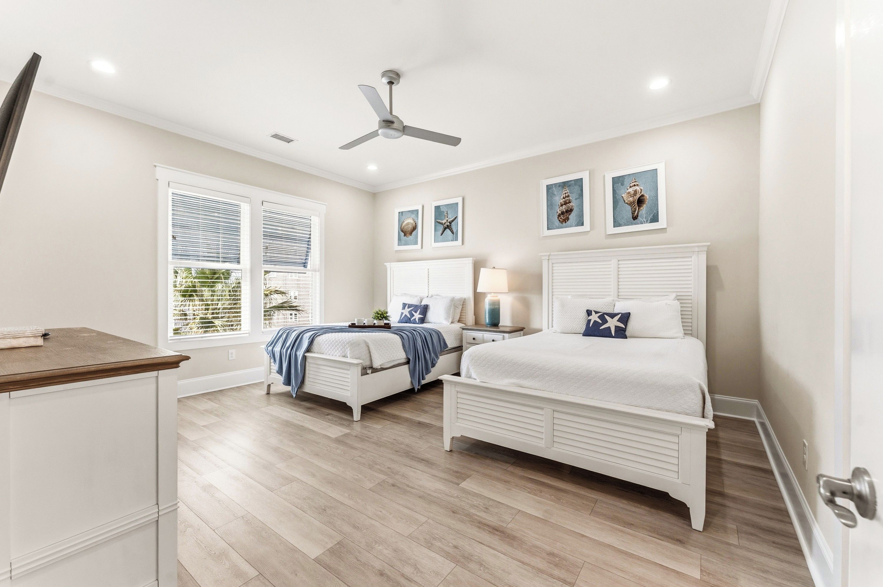 A bedroom with a bed, bedside tables, a ceiling fan, and artwork on the wall.