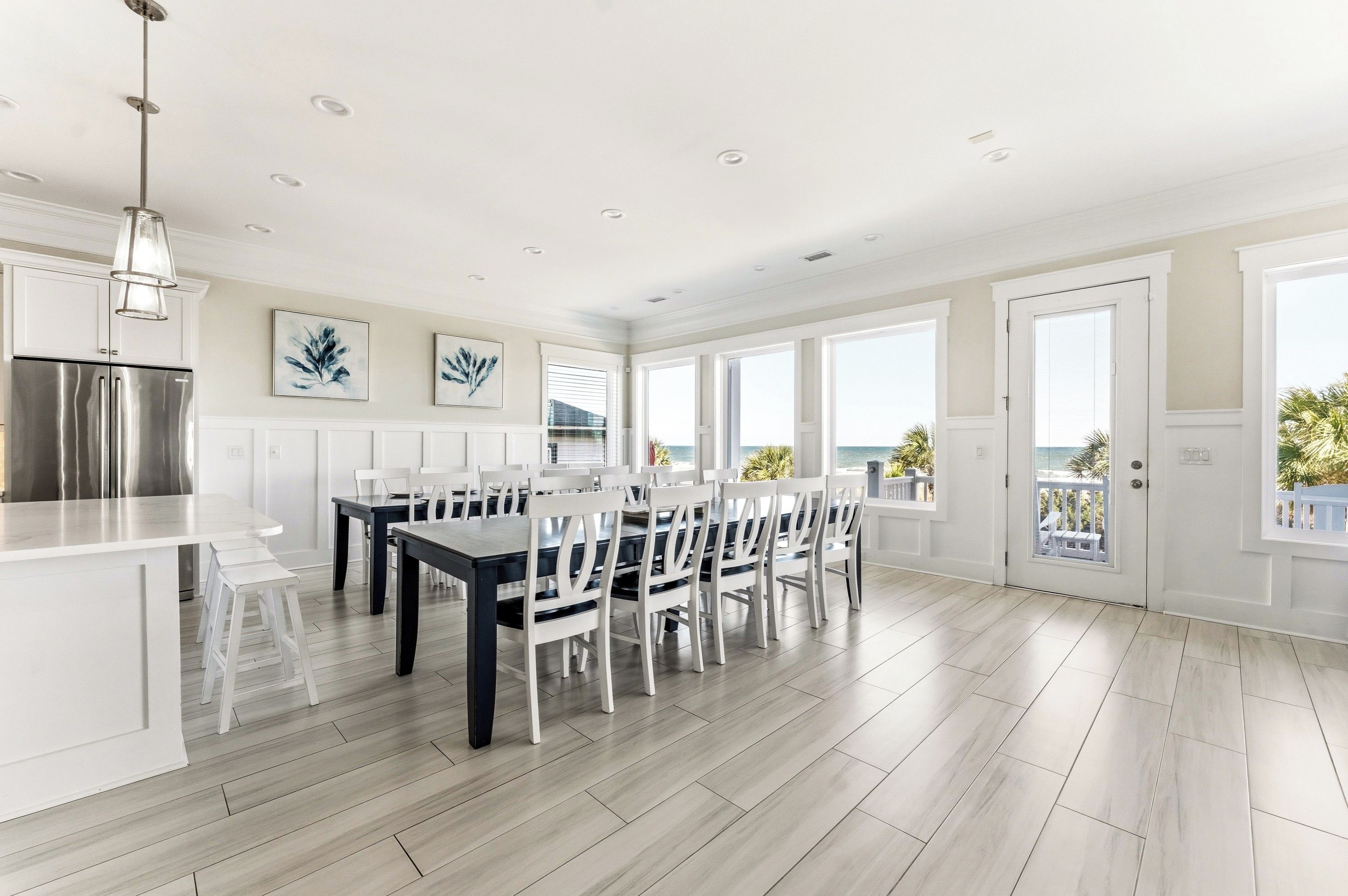 A spacious kitchen with a large island, white cabinetry, and a stainless steel refrigerator.