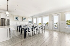A spacious kitchen with a large island, white cabinetry, and a stainless steel refrigerator.