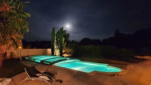 Una piscina dalle linee curve, circondata da lettini e una palma.