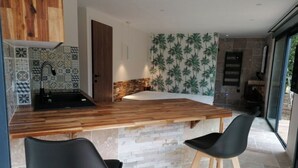 Una cucina moderna con un piano di lavoro in legno, due sgabelli neri e uno schienale in pietra.