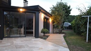 Una casa moderna con patio, ampie vetrate e un piccolo albero.
