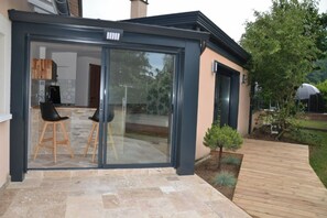 Une maison moderne dotée d’une grande porte-fenêtre coulissante qui donne sur un patio extérieur.